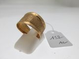 une image d'un gros plan d'une bague en or sur une surface blanche