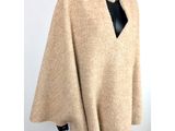a woman wearing a beige ponche with a black top