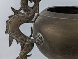 a metal vase with a dragon on it on a stand