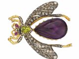un gros plan sur une broche en forme de libellule ornée d'une fleur violette