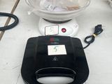 un grille-pain noir et blanc posé sur une table à côté d'un bol de nourriture