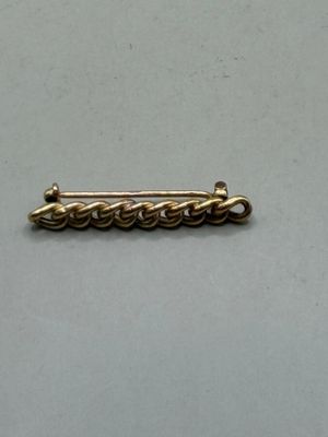 a close up of a gold plated pin with a chain on it