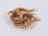 a gold brooch with diamonds on it on a white surface