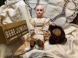 a doll that is sitting on a bed with a teddy bear