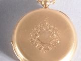 a gold pocket watch that is hanging on a string