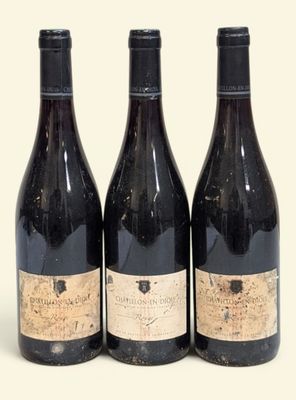 trois bouteilles de vin posées les unes à côté des autres sur une surface blanche