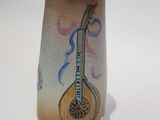 a vase with a guitar on it on a white surface