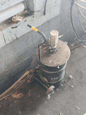 a black bucket with a yellow handle sitting next to a wall