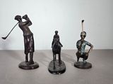 trois figurines représentant un homme et une femme jouant au golf