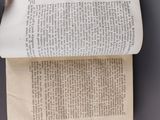 an overhead view of a person ' s hand holding an open book on a table