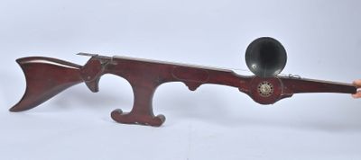 Quelqu'un tient un fusil en bois dont le canon est noir.