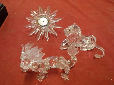 three glass figurines on a table with a clock