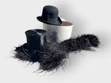 deux chapeaux et une plume posés sur une table blanche