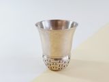 a silver cup sitting on top of a yellow and white table