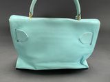 a close up of a blue handbag on a gray background