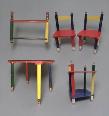 four different colored desks with pencils on them on a gray surface