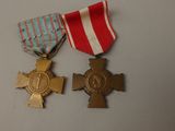 two medals and a cross on a table with a red and white striped ribbon