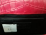a red purse with a tag on it sitting on a table