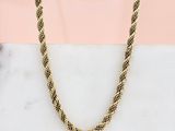 une photo d'un collier à chaîne en or posé sur une surface en marbre