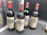 four bottles of wine are lined up in a row on a window sill