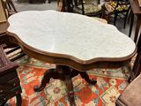 une table au plateau en marbre dans une pièce remplie de meubles anciens
