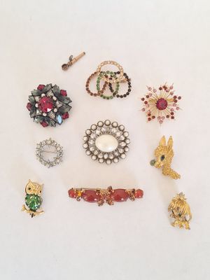 several different brooches and pins are arranged on a white surface