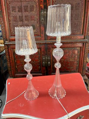 une paire de lampes de table en verre transparent posées sur une table rouge devant une armoire rouge