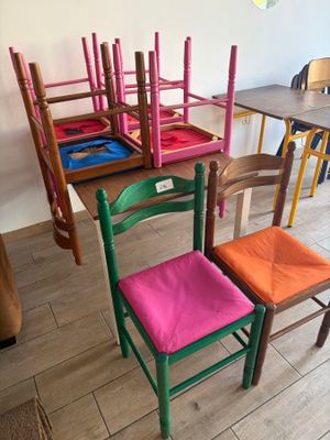 Des chaises aux couleurs vives sont alignées en rang devant une table