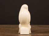 white bird figurine sitting on a wooden table with a black background