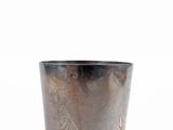 a close up of a metal cup with a bird design on it