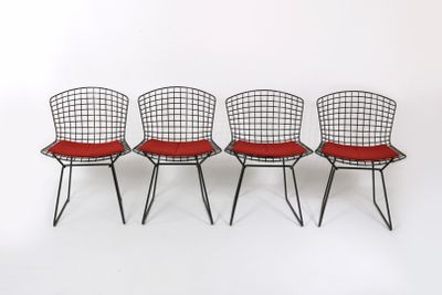 trois chaises en fil de fer noires avec des coussins rouges sur fond blanc