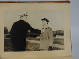 black and white photo of a man in uniform shaking another man ' s hand