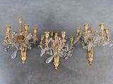 three antique brass and crystal wall sconces on a gray background