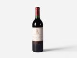 a bottle of red wine sitting on top of a white table