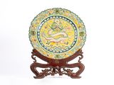 une assiette décorative ornée d'un dragon, posée sur un socle