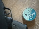 a can of paint next to a gun on a wooden floor