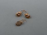 deux paires de boucles d'oreilles en or posées sur une surface grise