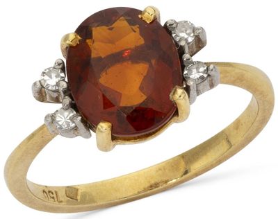 a close up of a gold ring with a red stone and diamonds