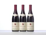 three bottles of red wine sit on a white surface