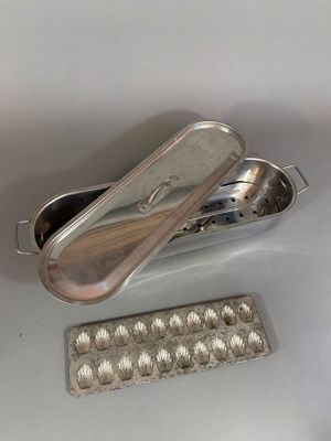 a silver container with a spoon in it next to a tray of eggs