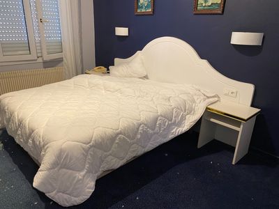 a white bed in a blue room with a white headboard