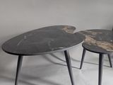 two tables with black marble tops sit on a white surface