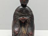 une vieille statue en bois représentant une femme tenant une fleur