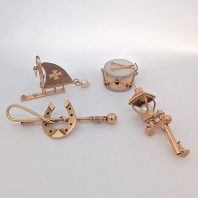trois objets nautiques plaqués or sont exposés sur un fond blanc