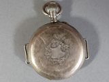 a silver pocket watch with a silver face on it