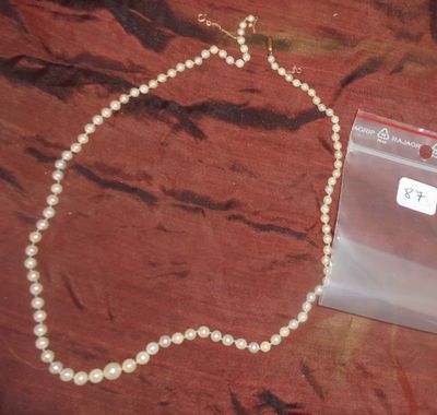 un collier de perles blanches et un sac en plastique posés sur une table