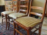 four wooden chairs in a room with a rug on the floor