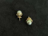 a pair of pearl and gold earrings on a black surface