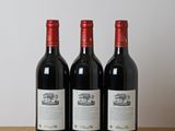 three bottles of wine sitting on a wooden table next to a bottle of wine