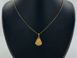 a gold necklace with a tear shaped pendant on a black mannequin